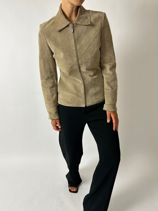 Person wearing a beige suede jacket on a white background
