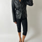 Person wearing a black leather jacket and pants on a plain background