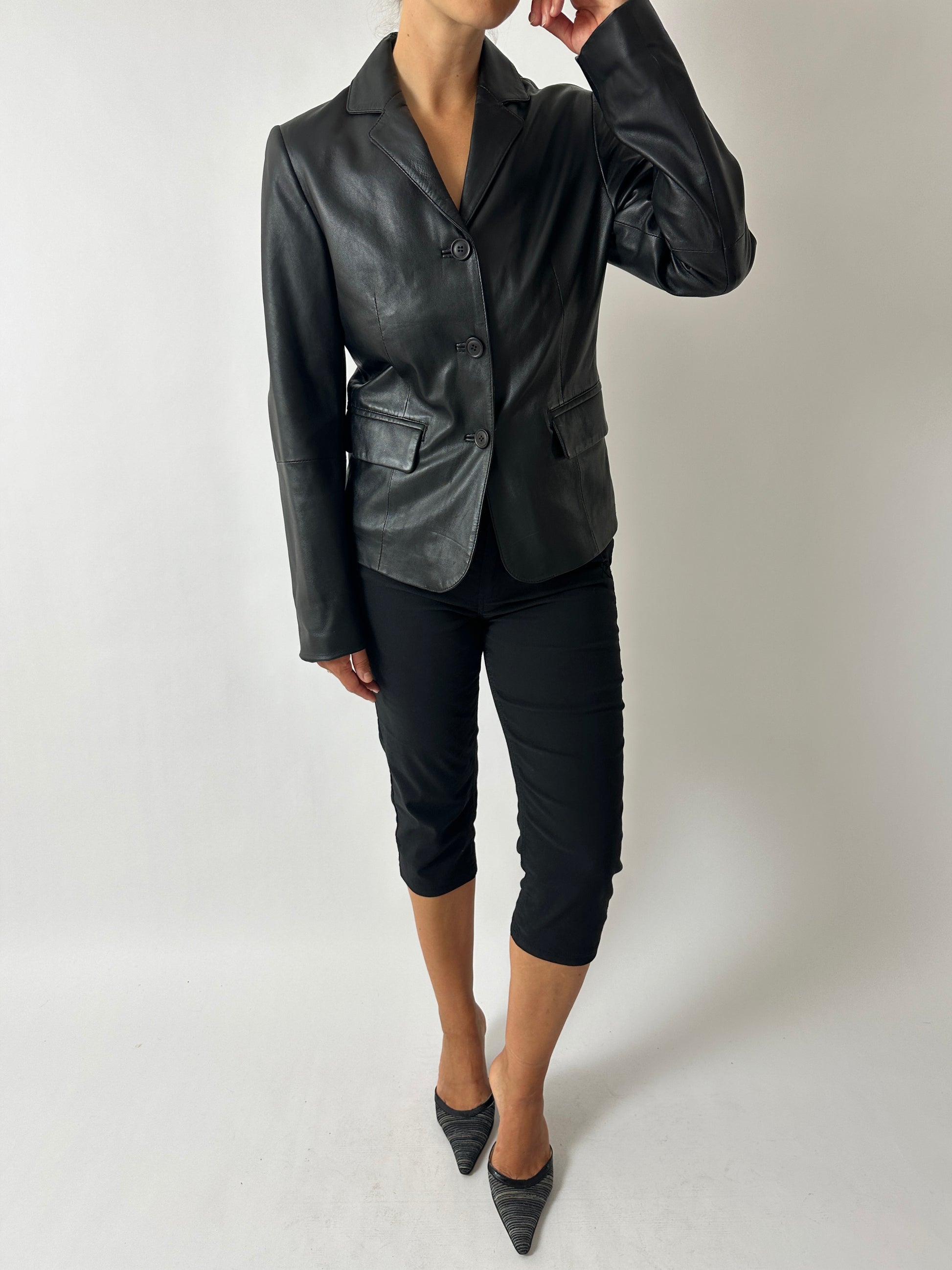Person wearing a black leather jacket and pants on a plain background