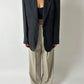 Person wearing a black blazer and beige pants on a plain background