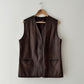 Brown leather vest on a wooden hanger against a white background