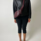 Vintage leather jacket with funnel neck worn with pre-loved leather crossbody bag with moon shape in bordeaux color
