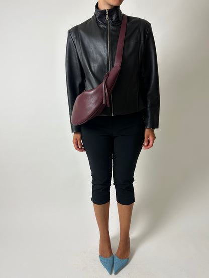 Vintage leather jacket with funnel neck worn with pre-loved leather crossbody bag with moon shape in bordeaux color